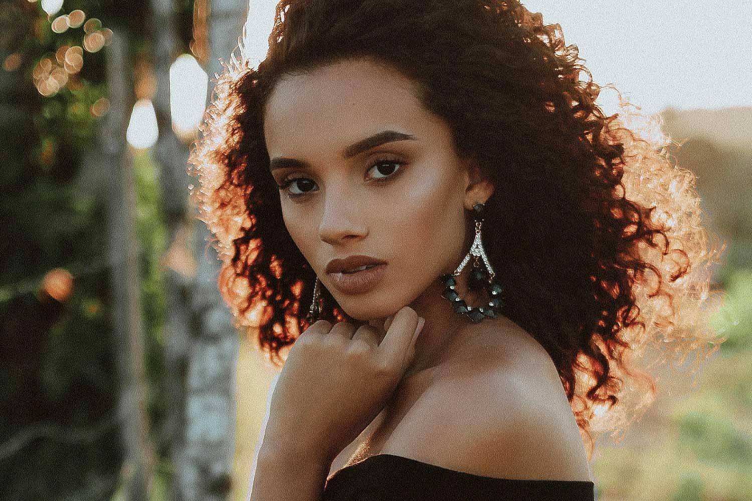 Portrait of a woman with curly hair outdoors.