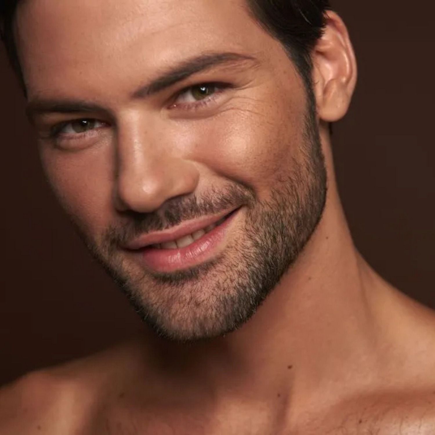 Smiling man with beard against dark background.