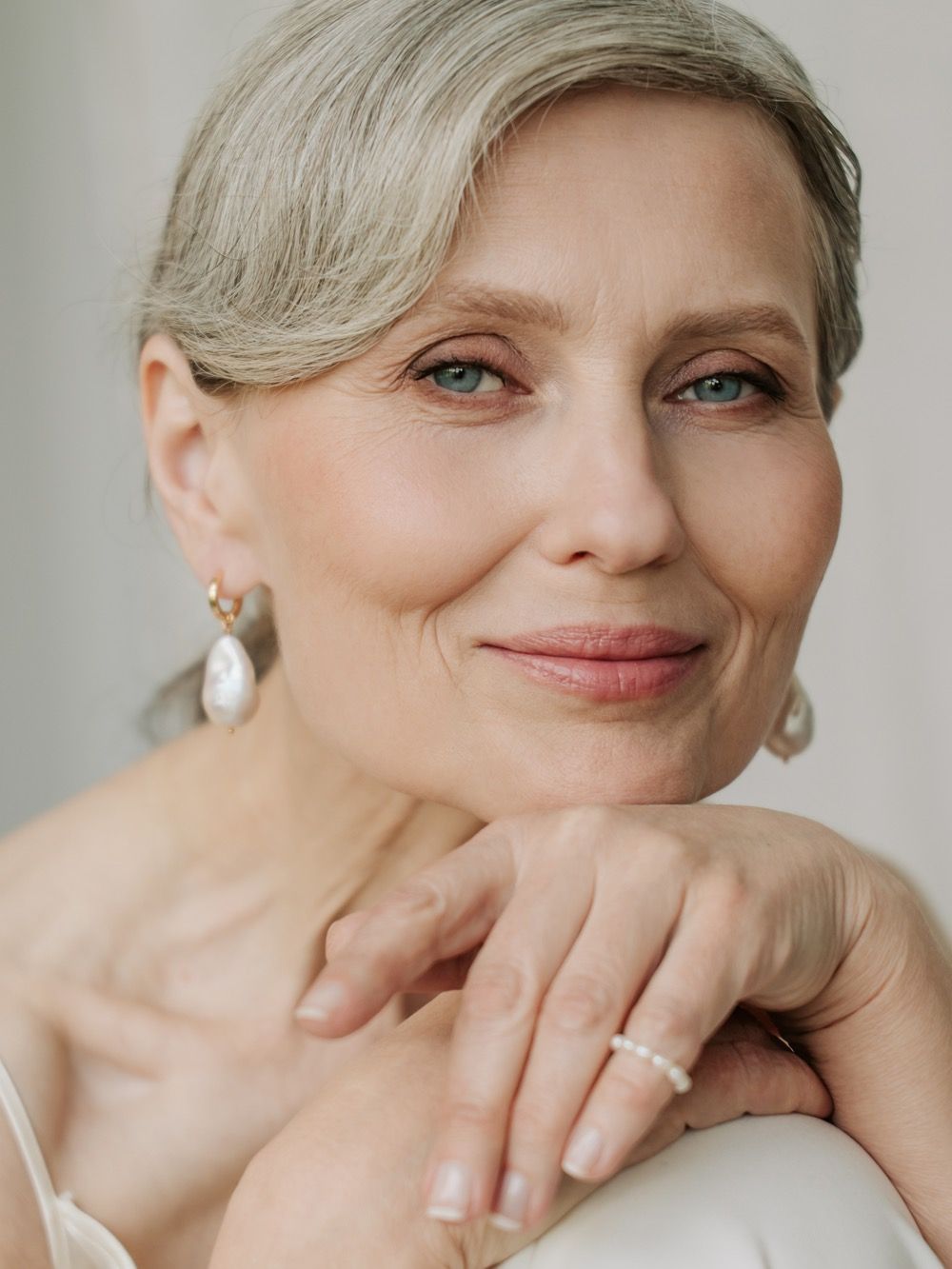 Smiling older woman with elegant hairstyle and accessories.