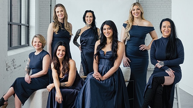 Group of women in elegant dresses posing together.
