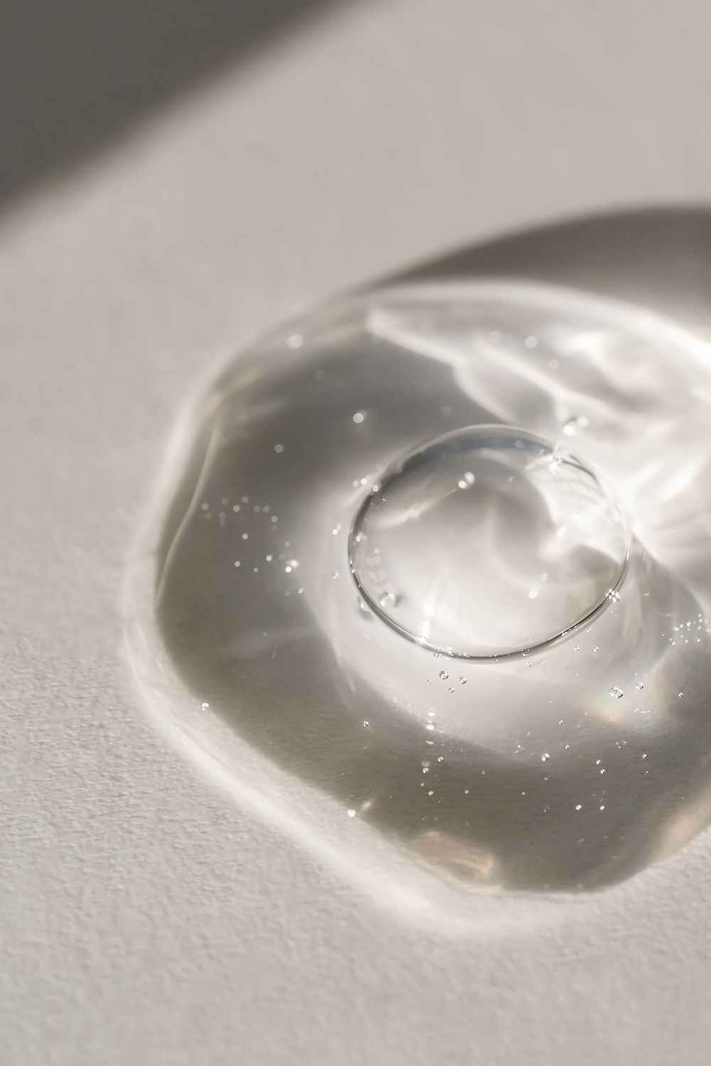 Clear gel droplet on white surface.