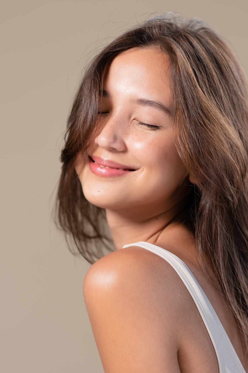 Smiling woman with long hair against neutral background.
