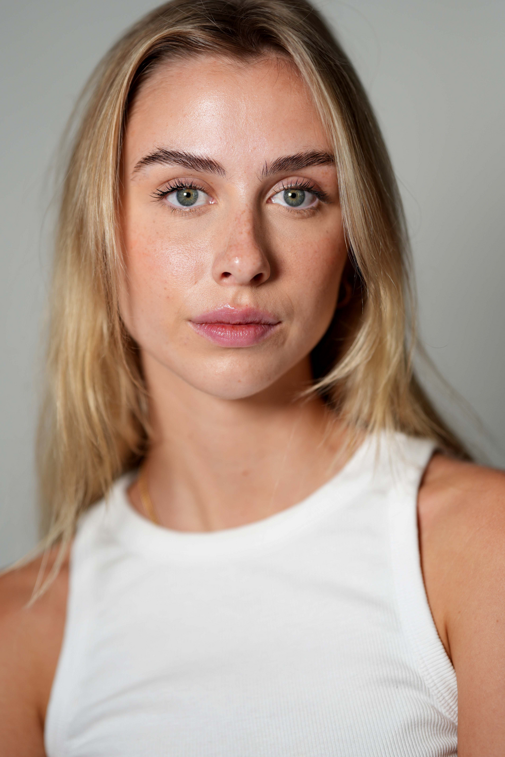 Portrait of a woman with blonde hair, neutral background.