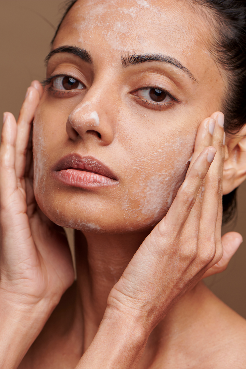 Woman applying cleanser to her face.