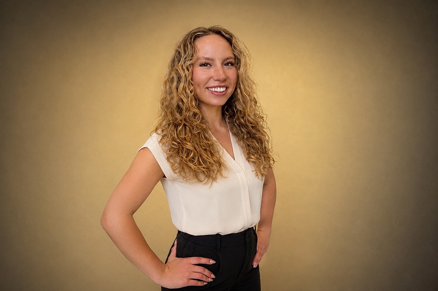 Smiling person with curly hair in formal attire.