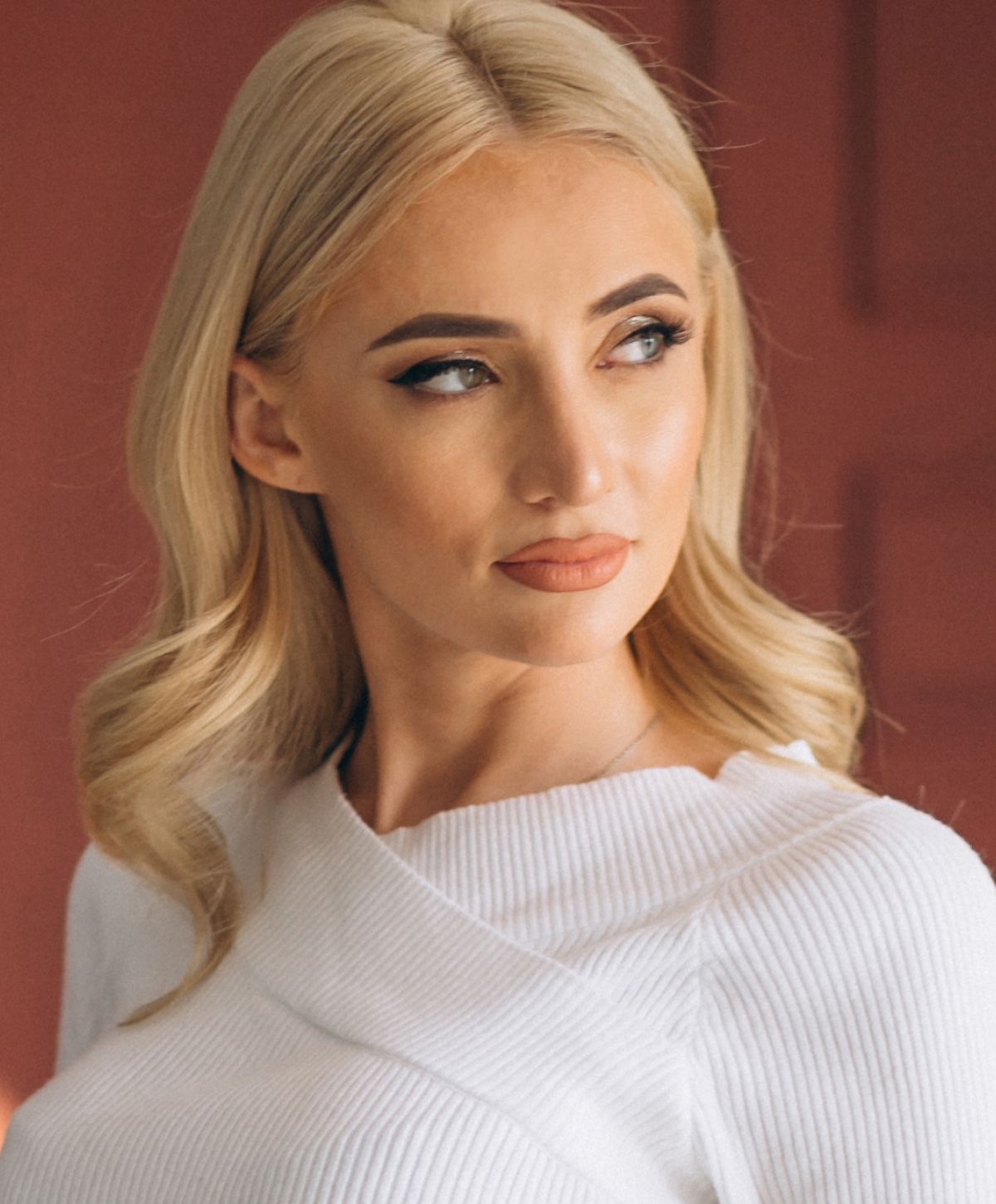 Woman with blonde hair wearing a white top.