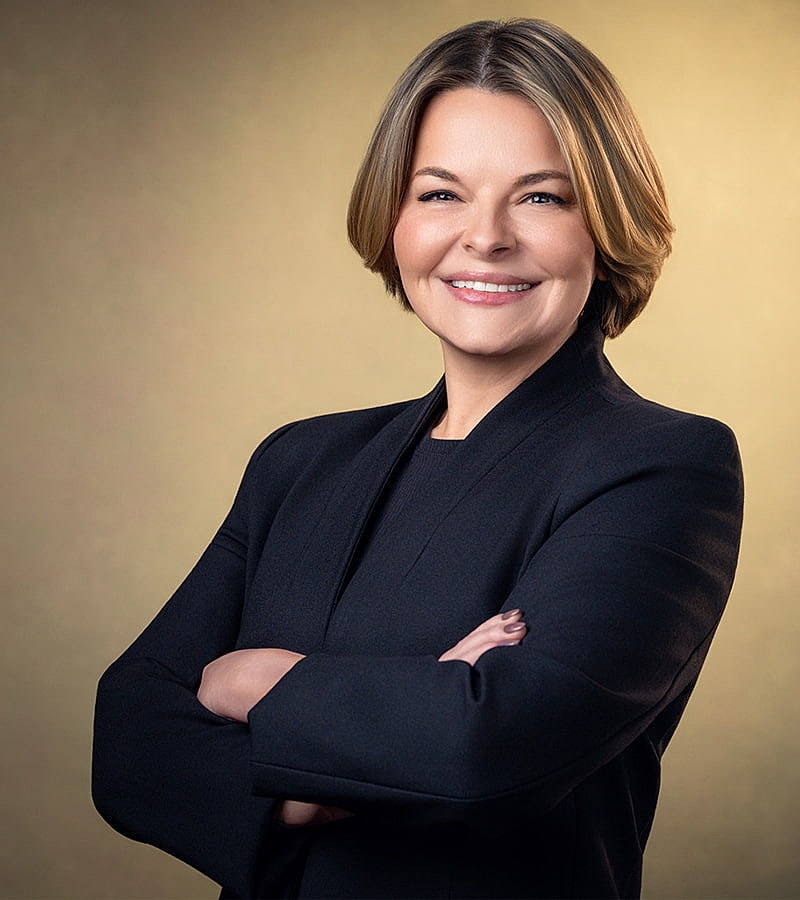 Woman with long hair and glasses smiling.