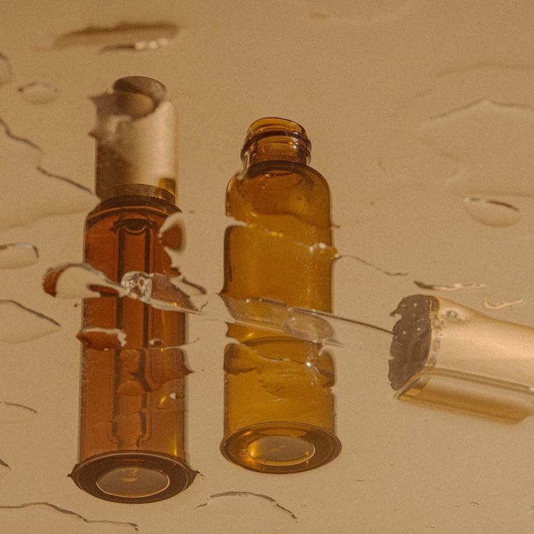 Two cosmetic bottles reflected in water.