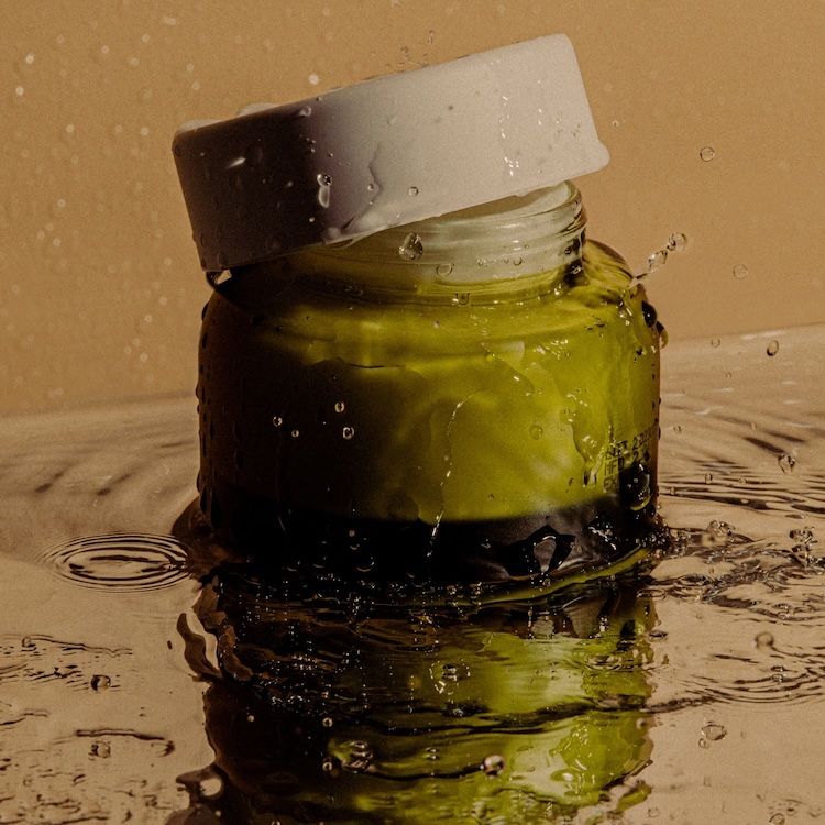 Jar of moisturizer splashing in water.