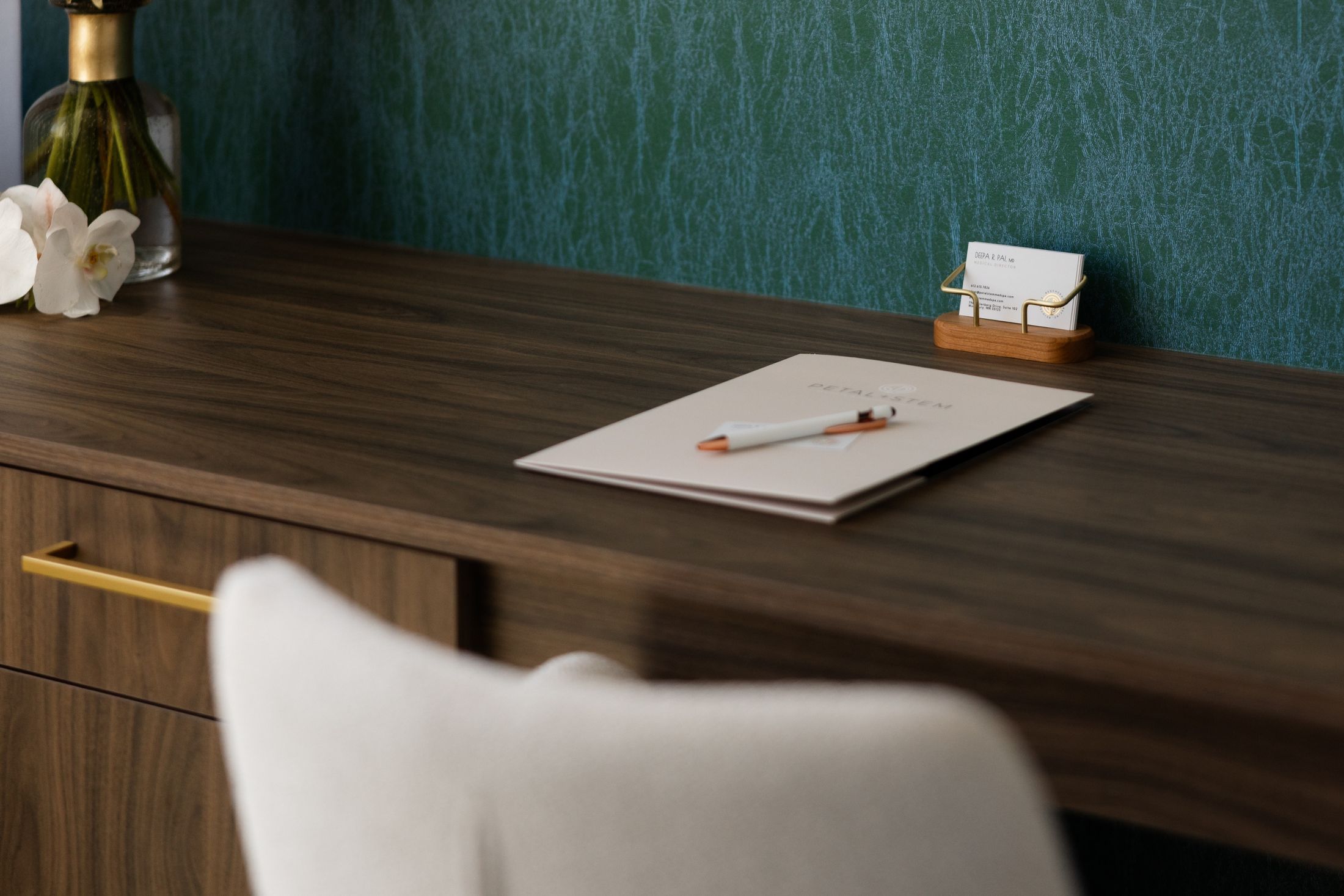 Elegant desk with stationery and flower vase.