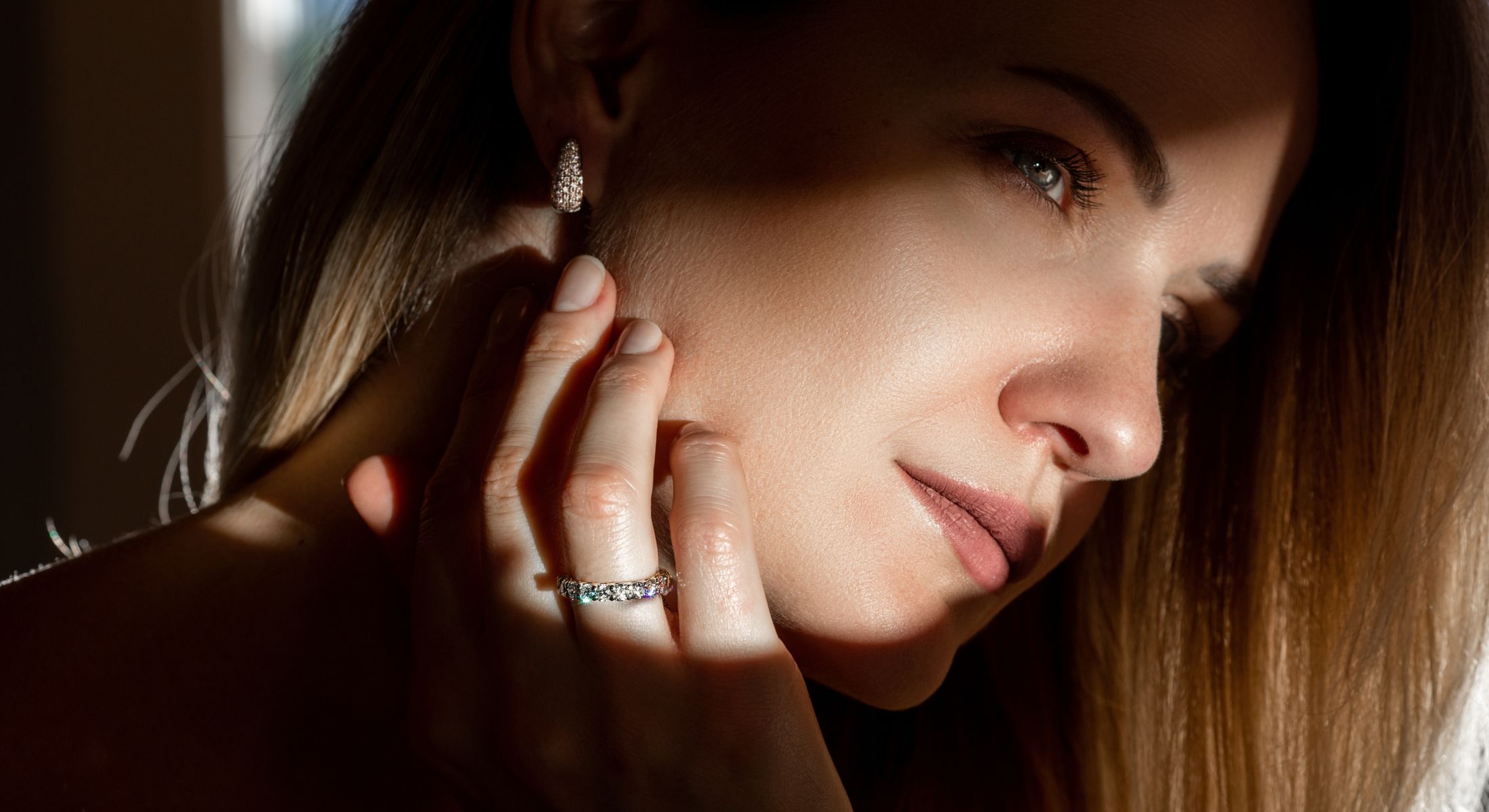 Woman with jewelry in soft, dramatic lighting.