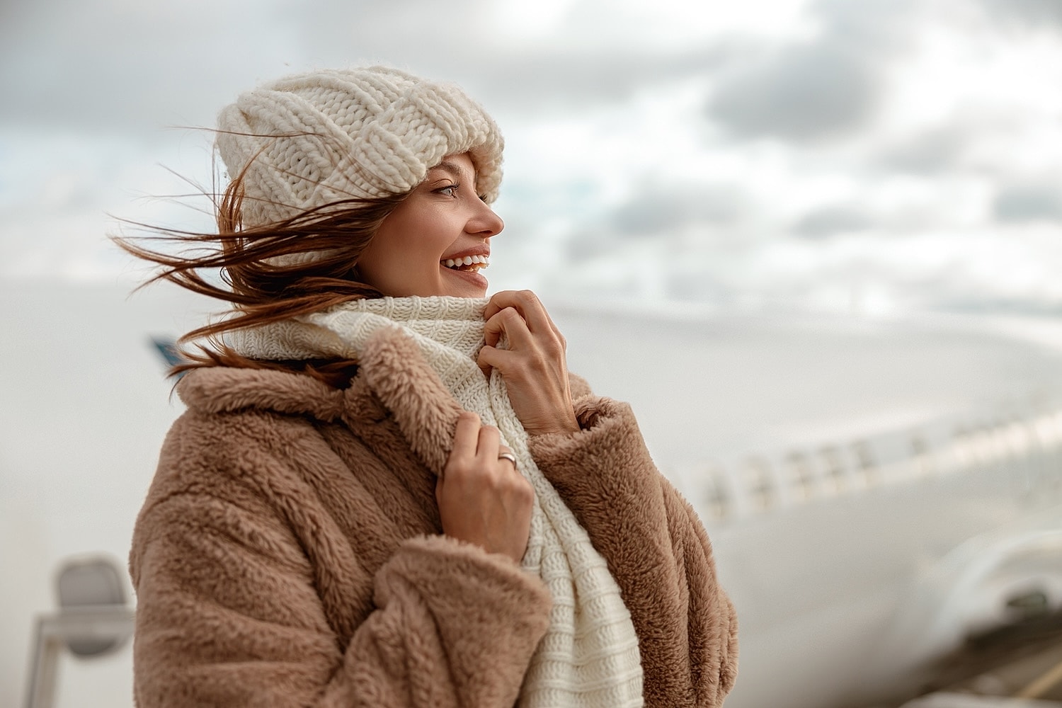 Smiling woman in cozy winter attire at airport.